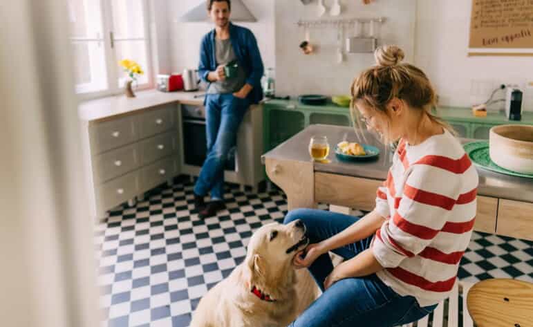 A couple with their healthy and happy dog in the kitchen.